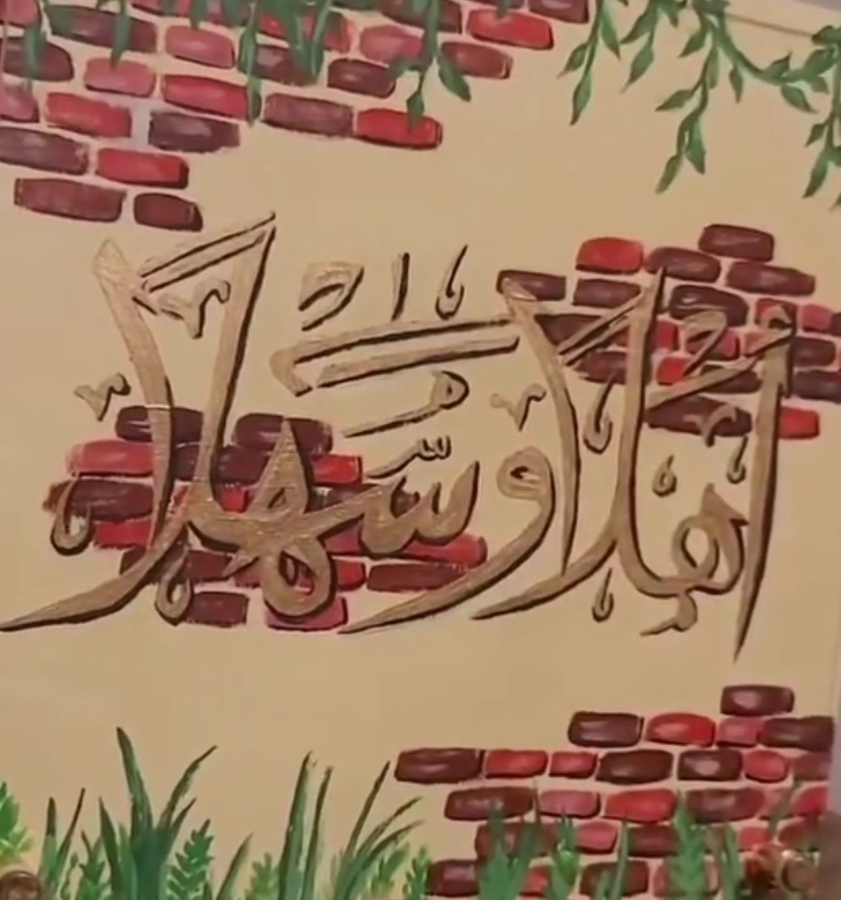 Arabic Ahlan wa Sahlan welcome calligraphy painting with brick wall and greenery